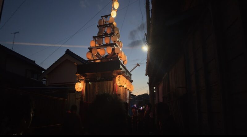 夕暮れの路地に灯る祭りの山車